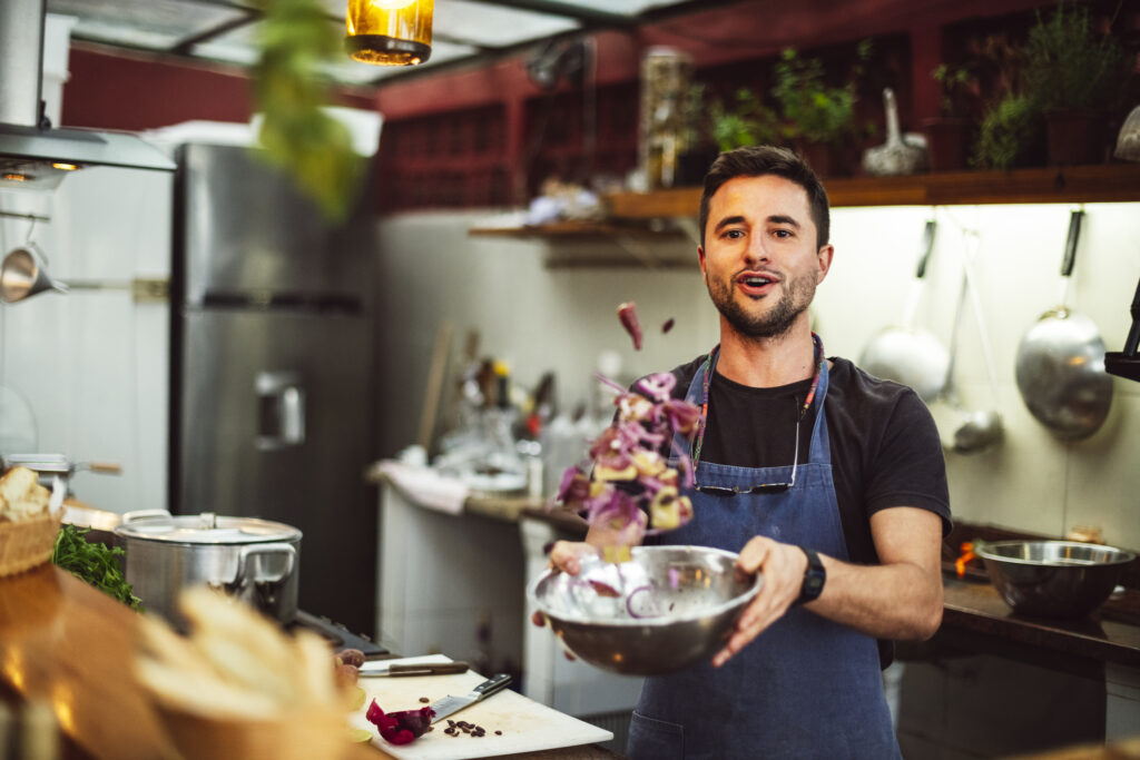 Porträt eines männlichen Kochs der Zutaten in einer Schüssel schwenkt